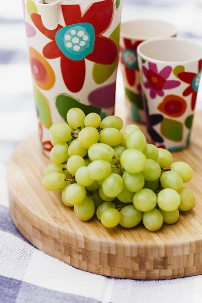 Grapes and drinks on cutting board — Stock Photo, Image