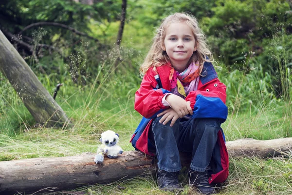 Liten flicka sitter på en gren — Stockfoto