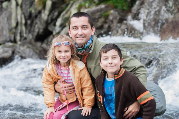 Familia sentada cerca del arroyo de montaña — Foto de Stock