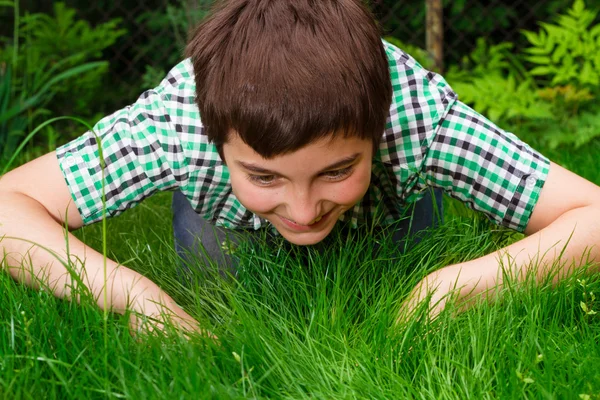 Rapaz à procura de vida na grama — Fotografia de Stock