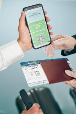 Dijital covid sertifikası. Kapsamlı aşı dijital geçiş kartı. Cep telefonu, pasaport ve uçak biletinde dijital kimlik kartı olan bir kadın. Sayısal covid test sonuçlarını covid-19 salgınında seyahat için tıbbi geçiş olarak gösteren bir gezgin