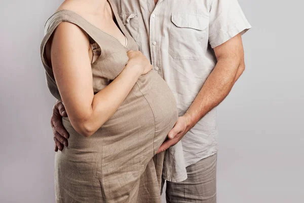 Pregnant Woman Her Husband Touching Her Tummy Standing Plain Background — Stock Photo, Image