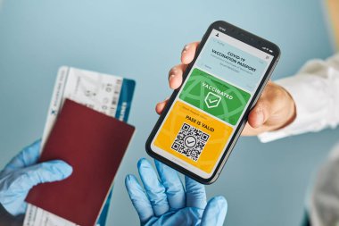 Dijital covid sertifikası. Kapsamlı aşı dijital geçiş kartı. Cep telefonu, pasaport ve uçak biletinde dijital kimlik kartı olan bir kadın. Sayısal covid test sonuçlarını covid-19 salgınında seyahat için tıbbi geçiş olarak gösteren bir gezgin