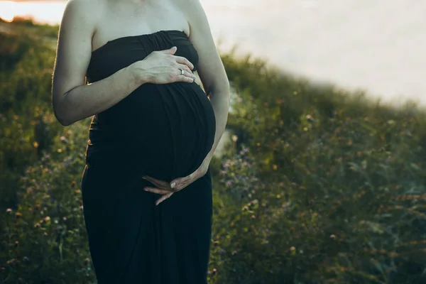 妊娠中の女性は自然に囲まれた屋外で彼女のおなか立って抱擁します 母親の概念 — ストック写真