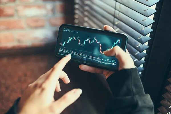 利用智能手机上的投资应用程序在股票加密货币市场上进行交易的人 股市投资在手 拿着手机看蜡烛图的商人 — 图库照片