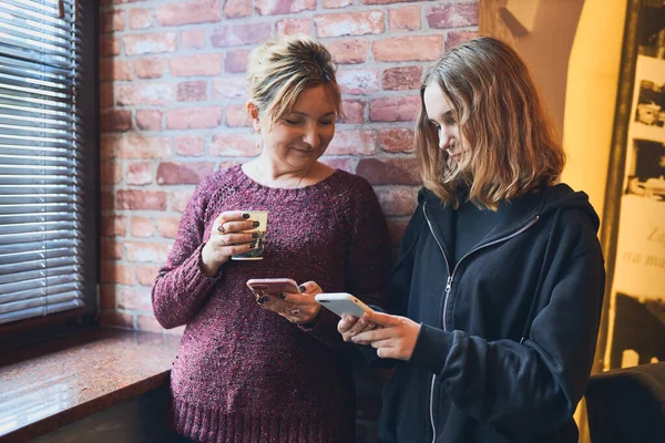 Uśmiechnięte Kobiety Korzystające Smartfonów Pijące Kawę Odpoczywające Biurze Podczas Przerwy — Zdjęcie stockowe