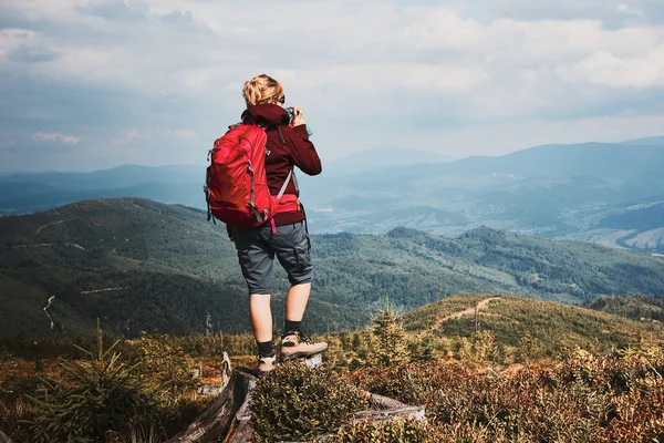 背着背包在山上远足的女人在大自然附近度过暑假 妇女站在山顶上欣赏山景全景的背景图 — 图库照片