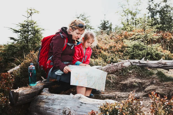 在山上的家庭旅行 妈妈和她的小女儿在看地图 坐在树桩上 暑假休息 — 图库照片