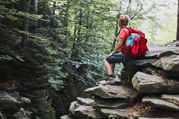 背着背包在山上远足的女人女人坐在岩石上休息 与大自然亲近的暑假 — 图库照片