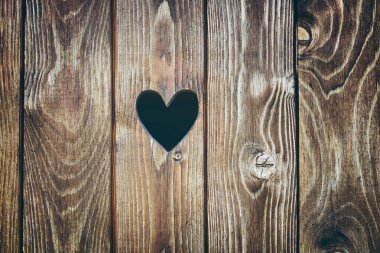 Kalp şeklinde deliği olan ahşap kapı. Ahşap doku arka planı. Eski rustik tahta yüzeyi