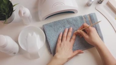 Kadın, ultraviyole lamba kullanarak jel cilası sürmeye hazırlanıyor. Güzellik sağlık spa tedavisi konsepti. Kozmetik ürünler, ultraviyole lamba, beyaz masada yeşil yapraklar. Spa, manikür, cilt bakımı konsepti. Düz uzan, yukarıdan bak.