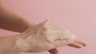 Kozmetik nemlendirici el kremi süren bir kadın. Kozmetik ürünler, beyaz masada yeşil yapraklar. Spa, manikür, cilt bakımı konsepti