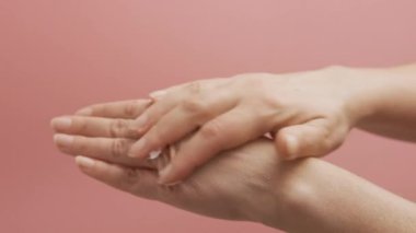 Kozmetik nemlendirici el kremi süren bir kadın. Kozmetik ürünler, beyaz masada yeşil yapraklar. Spa, manikür, cilt bakımı konsepti