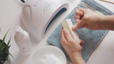 Kadın, ultraviyole lamba kullanarak jel cilası sürmeye hazırlanıyor. Güzellik sağlık spa tedavisi konsepti. Kozmetik ürünler, ultraviyole lamba, beyaz masada yeşil yapraklar. Spa, manikür, cilt bakımı konsepti. Düz uzan, yukarıdan bak.