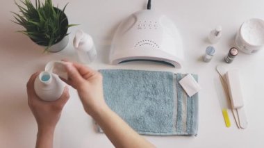 Kadın, ultraviyole lamba kullanarak jel cilası sürmeye hazırlanıyor. Güzellik sağlık spa tedavisi konsepti. Kozmetik ürünler, ultraviyole lamba, beyaz masada yeşil yapraklar. Spa, manikür, cilt bakımı konsepti. Düz uzan, yukarıdan bak.