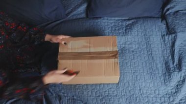 Anne ve kızı evdeki kanepede sipariş verdikleri elbiseyle birlikte kutuyu açıyorlar. Annem internetten alışveriş yapan müşterinin elbisesini tutuyor. Teslimat servisi moda konsepti