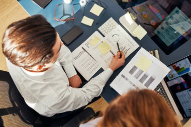 İş arkadaşları ofiste finansal verileri tartışıyor. Bilgisayarda çizelgeler ve masalarla çalışan girişimciler. Birlikte çalışan iki kişi. İş arkadaşları proje hakkında konuşuyor