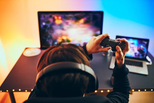 男人在家里玩电子游戏 游戏玩家手持游戏面板坐在屏幕前 流线型游戏在黑暗的房间里由霓虹灯照明 竞争与玩乐 — 图库照片