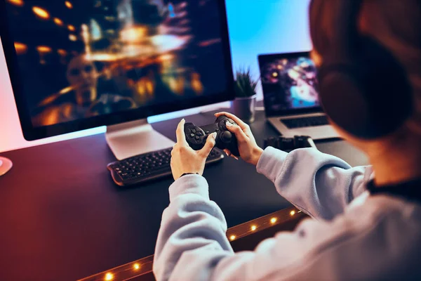 在家里玩电子游戏的少女 游戏玩家手持游戏面板坐在屏幕前 流线型游戏在黑暗的房间里由霓虹灯照明 竞争与玩乐 — 图库照片