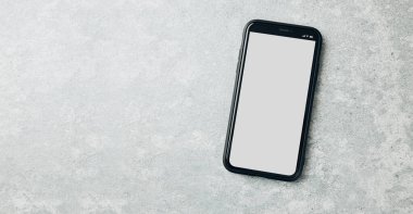 Mermer zemin üzerinde boş beyaz renkli boş bir ekran ile akıllı telefon modeli. Siyah cep telefonu üst görünümü düz ve fotokopi alanı var. İçerik için hazır. Metin için yer