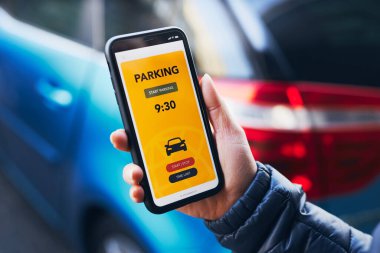 Akıllı telefondan mobil park uygulaması kullanan bir kadın. Şoför park ücretini ödemek için akıllı telefonu kullanıyor. Cep telefonundan otopark başvurusu. Çevrimiçi hızlı ödemeyle park ücretini ödemeye elverişli. Mobil park servisi