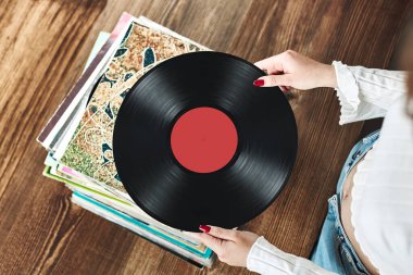 Vinil plak çalıyorum. Vinil pikaptan müzik dinliyordum. Retro ve klasik müzik tarzı. Analog LP albüm tutan bir kadın. Eski plaklar yığını. Müzik koleksiyonu. Müzik tutkusu