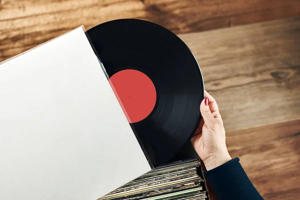 Playing vinyl records. Listening to music from vinyl record player. Retro and vintage music style. Woman holding analog LP record album. Stack of old records. Music collection. Music passion