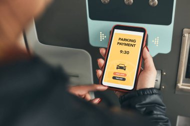 Bir kadın akıllı telefondaki mobil uygulamayı kullanarak araba park yeri ödeme makinesinin parasını ödüyor. Şoför park ücretini ödemek için akıllı telefonu kullanıyor. Cep telefonundan otopark başvurusu. Çevrimiçi hızlı ödemeyle park ücretini ödemeye elverişli. Mobil park se