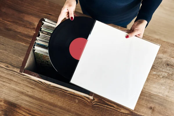 Playing vinyl records. Listening to music from vinyl record player. Retro and vintage music style. Woman holding analog LP record album. Stack of old records. Music collection. Music passion