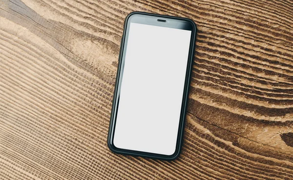 Ahşap zemin üzerinde beyaz, boş ve izole bir ekran olan akıllı telefon modeli. Siyah cep telefonu üst görünümü düz ve fotokopi alanı var. İçerik için hazır. Metin için yer