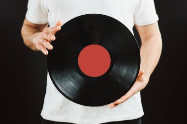 Plak kaydı olan bir adam. Klasik müzik tarzı. Siyah arka planda duran siyah analog diski tutan bir erkek. Retro müzik. Klasik ses.