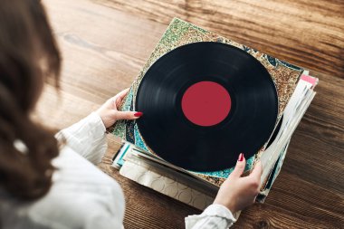 Vinil plak çalıyorum. Vinil pikaptan müzik dinliyordum. Retro ve klasik müzik tarzı. Analog LP albüm tutan bir kadın. Eski plaklar yığını. Müzik koleksiyonu. Müzik tutkusu