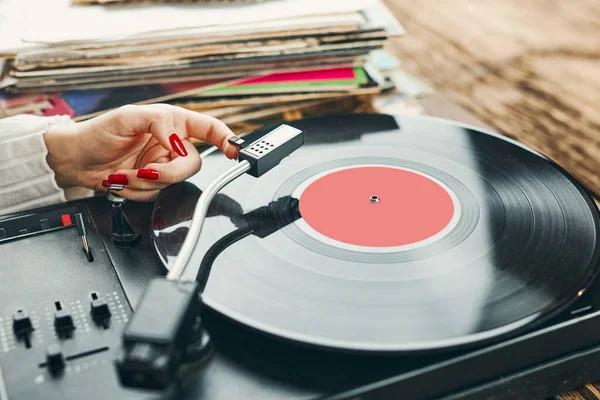 Vinil pikaptan müzik dinleyen genç bir kadın. Pikapta müzik çalıyor. Kadın, evdeki eski plak koleksiyonundan müziğin keyfini çıkarıyor. Analog vinil plak yığını. Retro ve klasik müzik tarzı. Müzik tutkusu ve hobisi