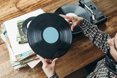 Vinil plaktan müzik dinleyen bir adam. Plak çalar üzerinde analog diskten müzik çalmak. Eski koleksiyonumdan müziğin tadını çıkarıyorum. Evde dinleniyorum. Retro ve antika. Müzik tutkusu