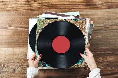 Vinil plak çalıyorum. Vinil pikaptan müzik dinliyordum. Retro ve klasik müzik tarzı. Analog LP albüm tutan bir kadın. Eski plaklar yığını. Müzik koleksiyonu. Müzik tutkusu