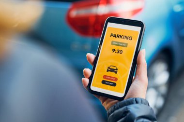 Woman using mobile parking app on smartphone. Driver using smartphone to pay for parking. Car park application on mobile phone. Convienience paying for parking using fast payment online. Mobile park service