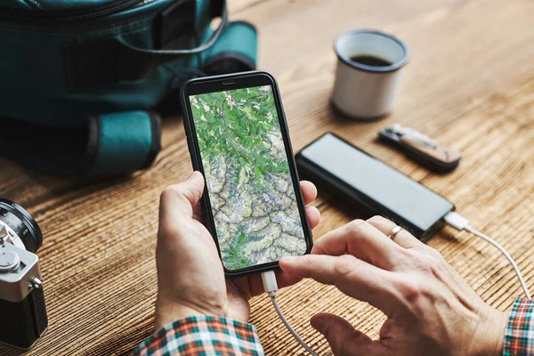 인간은 여행을 계획하고 있으며 목적지와 경로를 휴대폰으로 탐색하고 뱅크로 스마트폰 — 스톡 사진