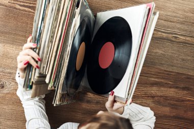 Playing vinyl records. Listening to music from vinyl record player. Retro and vintage music style. Woman holding analog LP record album. Stack of old records. Music collection. Music passion