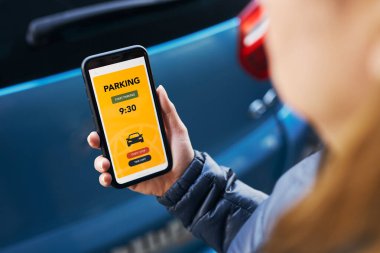 Akıllı telefondan mobil park uygulaması kullanan bir kadın. Şoför park ücretini ödemek için akıllı telefonu kullanıyor. Cep telefonundan otopark başvurusu. Çevrimiçi hızlı ödemeyle park ücretini ödemeye elverişli. Mobil park servisi