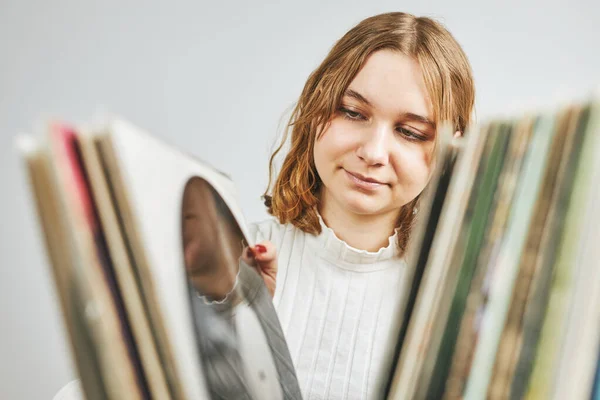 Playing vinyl records. Listening to music from vinyl record player. Retro and vintage music style. Young woman searching analog LP record album in stack of old records. Music collection. Music passion