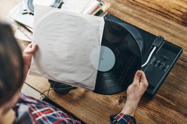 Vinil plaktan müzik dinleyen bir adam. Plak çalar üzerinde analog diskten müzik çalmak. Eski koleksiyonumdan müziğin tadını çıkarıyorum. Evde dinleniyorum. Retro ve antika. Müzik tutkusu