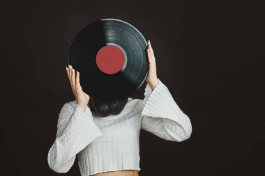 Elinde plak plağı tutan bir kadın. Müzik tutkusu. Analog kayıtlardan müzik dinlemek. Plak çalar üzerinde analog diskten müzik çalmak. Eski koleksiyonumdan müziğin tadını çıkarıyorum. Retro ve antika. Stereo sesi. Analog sesi