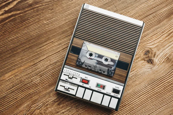 Compact cassette tapes and cassette recorder on wooden table. Retro music style. 80s music party. Vintage style. Analog equipment. Stereo sound. Back to the past