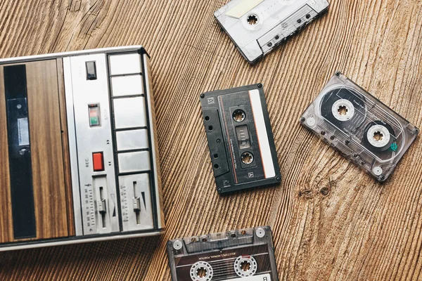 Compact cassette tapes and cassette recorder on wooden table. Retro music style. 80s music party. Vintage style. Analog equipment. Stereo sound. Back to the past