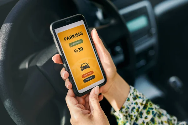 Woman using mobile parking app on smartphone. Driver using smartphone to pay for parking. Car park application on mobile phone. Convienience paying for parking using fast payment online. Mobile park service