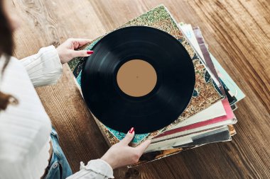 Vinil plak çalıyorum. Vinil pikaptan müzik dinliyordum. Retro ve klasik müzik tarzı. Analog LP albüm tutan bir kadın. Eski plaklar yığını. Müzik koleksiyonu. Müzik tutkusu