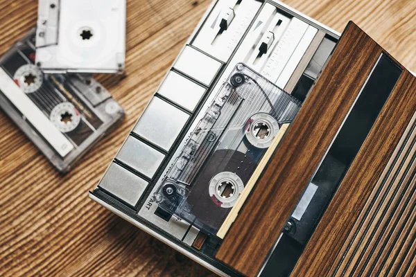 Compact cassette tapes and cassette recorder on wooden table. Retro music style. 80s music party. Vintage style. Analog equipment. Stereo sound. Back to the past