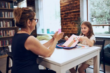 İlkokulda ders veren bir kadın. Okul sonrası klübünde masa başında oturan bir çocuk. Resim çizen kız. İlkokulda öğreniyorum. İlköğretim. Okula geri dön.