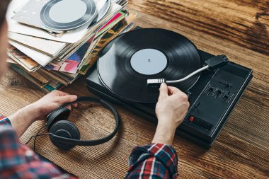 Vinil plaktan müzik dinleyen bir adam. Plak çalar üzerinde analog diskten müzik çalmak. Eski koleksiyonumdan müziğin tadını çıkarıyorum. Evde dinleniyorum. Retro ve antika. Müzik tutkusu