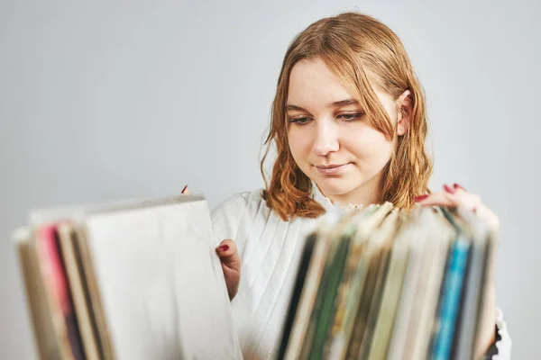 Playing vinyl records. Listening to music from vinyl record player. Retro and vintage music style. Young woman searching analog LP record album in stack of old records. Music collection. Music passion
